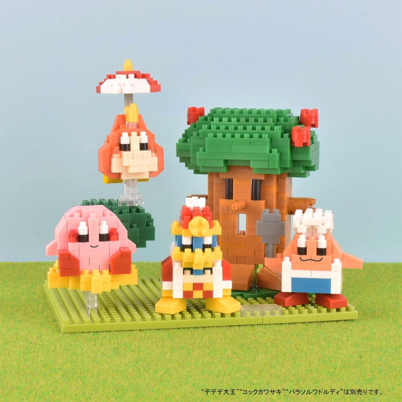 A group of colorful, pixelated characters from a video game, including a mushroom, a tree, and a character with a red hat, arranged on a green base.