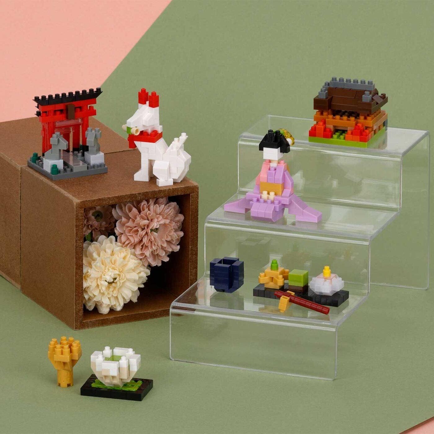 a collection of small, colorful toy figurines and a wooden box filled with flowers, all set against a green background.