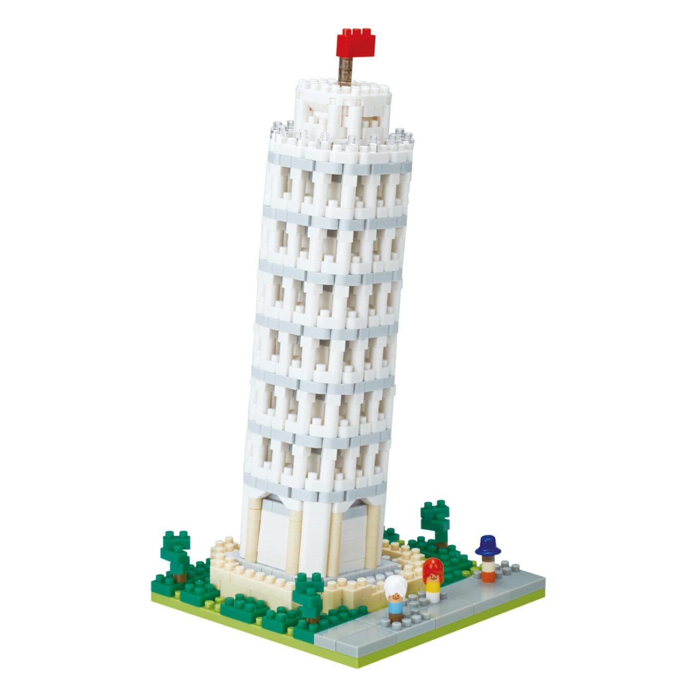 A white Lego tower with a red flag on top, surrounded by green Lego trees and figures.