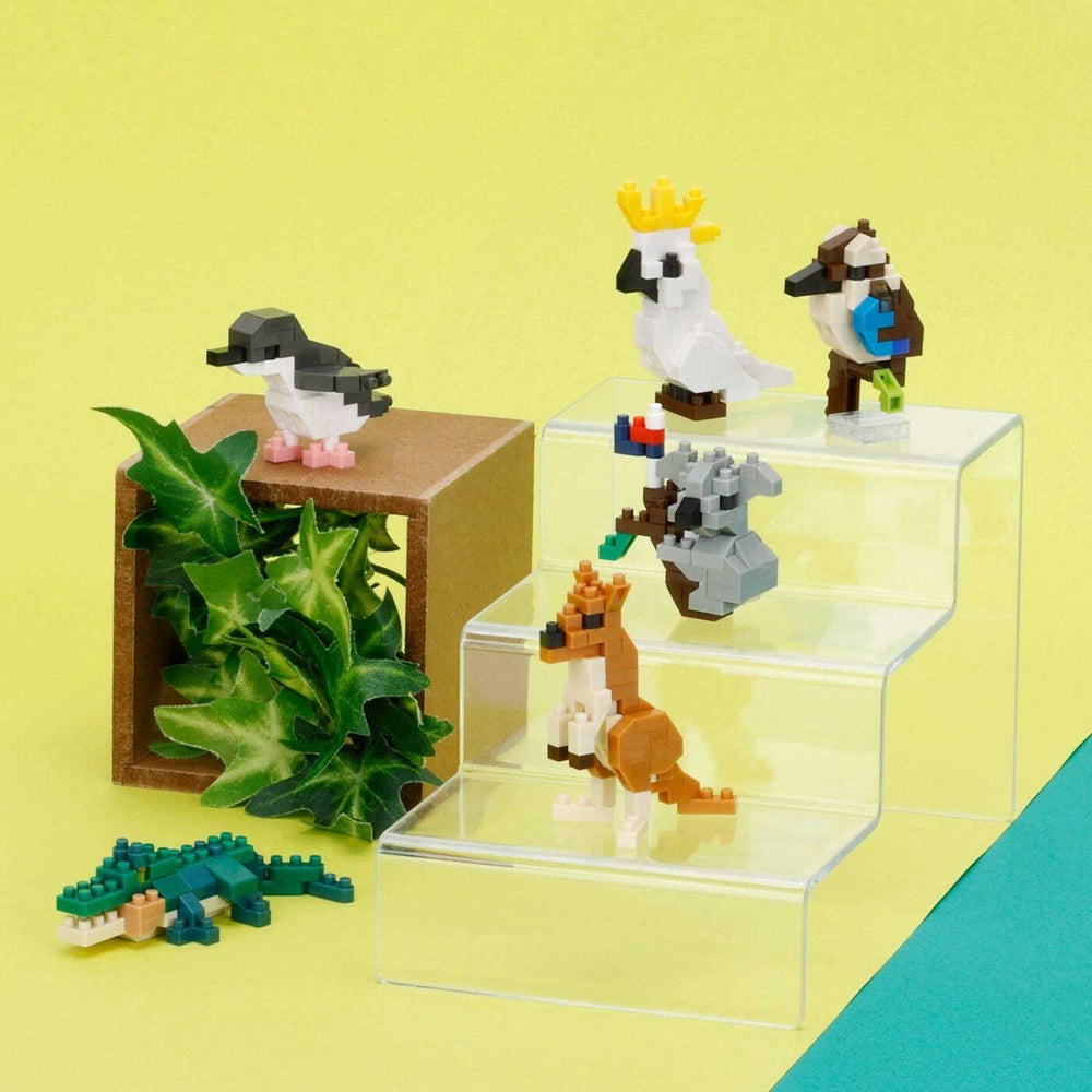 A collection of colorful, small toy animals, including a parrot, kangaroo, crocodile, and bird, arranged on a yellow background.