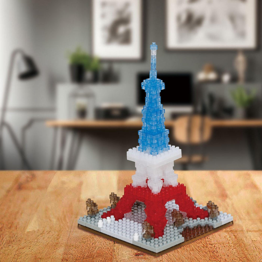 A small, colorful, and intricate model of the Eiffel Tower made of small, colorful building blocks is displayed on a wooden surface.