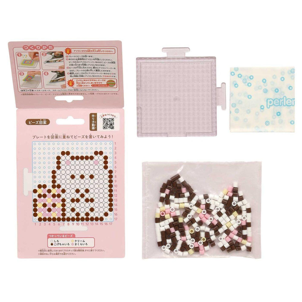 various items related to a craft or art project, including a pink box with instructions, a clear plastic container, and a bag filled with colorful beads.