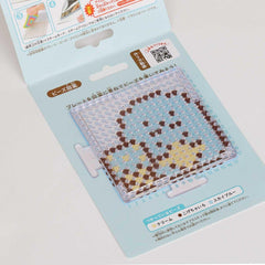 a product packaging for a craft item, specifically a bead board or bead mat. The packaging has a light blue background with a pattern of small circles and dots, and there is some text and a QR code visible on the packaging.