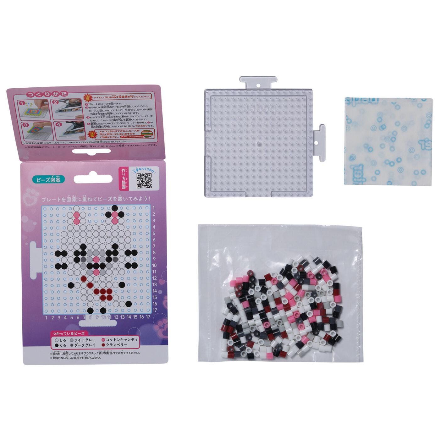 various items related to a craft or art project, including a box with instructions, a clear plastic container, and a bag filled with small, colorful beads or tiles.