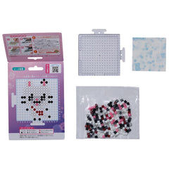 various items related to a craft or art project, including a box with instructions, a clear plastic container, and a bag filled with small, colorful beads or tiles.