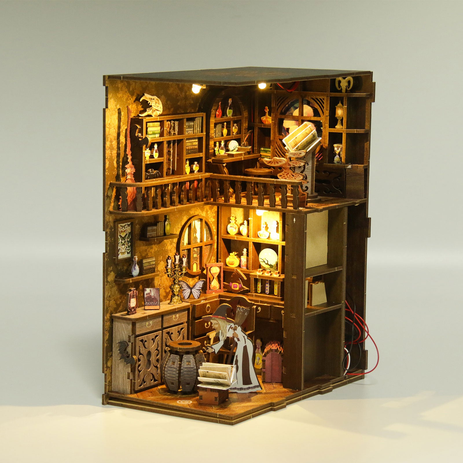 DIY book nook kit open cabinet with miniature kitchen shelves, table, and lit candles