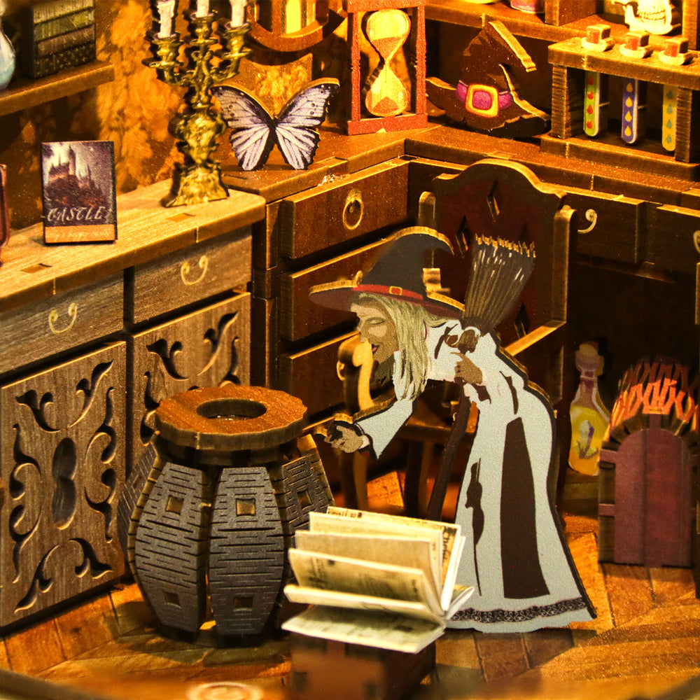 Miniature book nook scene with witch figure, stacked books, and candelabra on desk