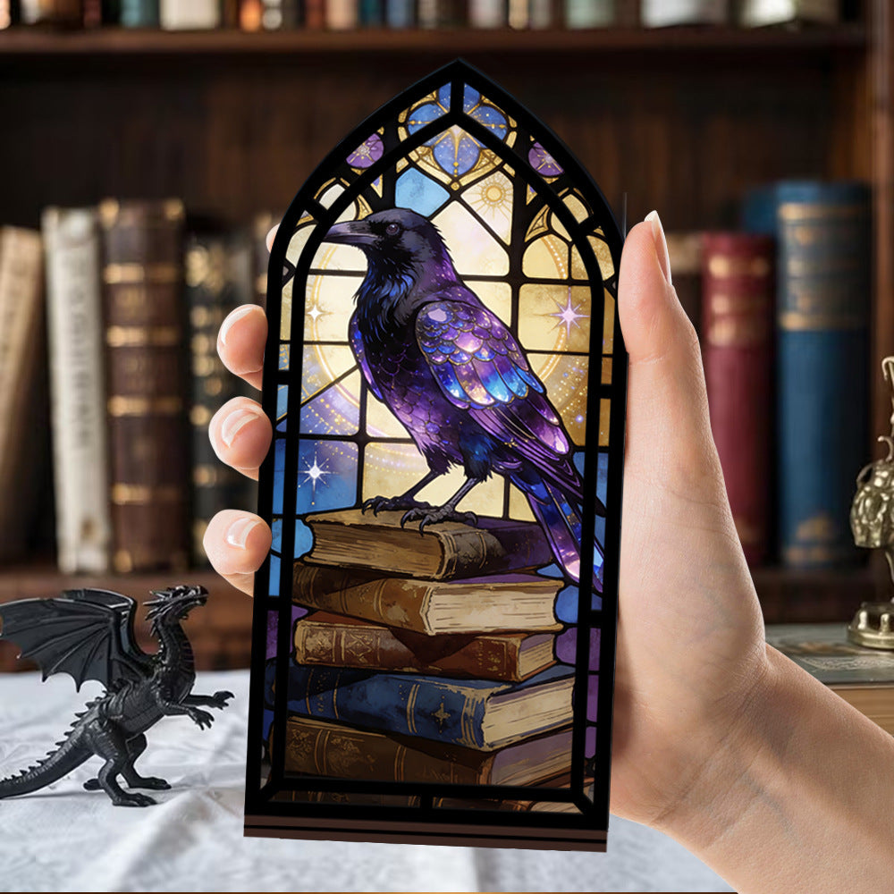 Hand holding arched book nook candle display with purple raven on book stack