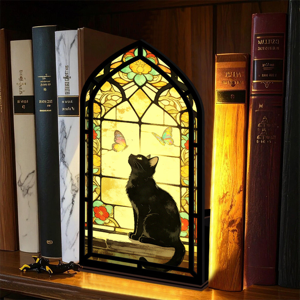 Stained glass arched book nook with black cat silhouette, colorful butterflies, and warm candle light