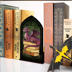 Dragon book nook with candle glow: arched black frame showing purple dragon on stacked books