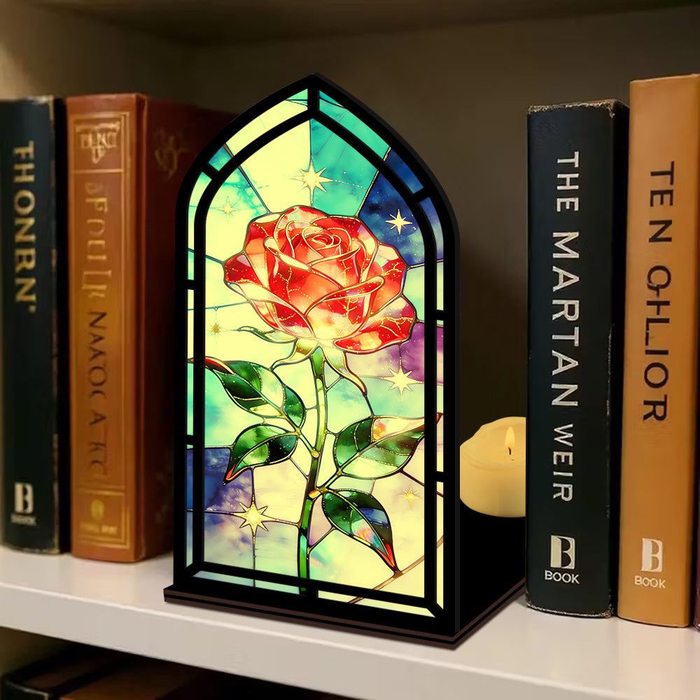 Black arched book nook with stained-glass red rose, with candle glow at the side