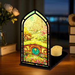 Small arched book nook with colorful illustrated panel and lit candle on a black base.