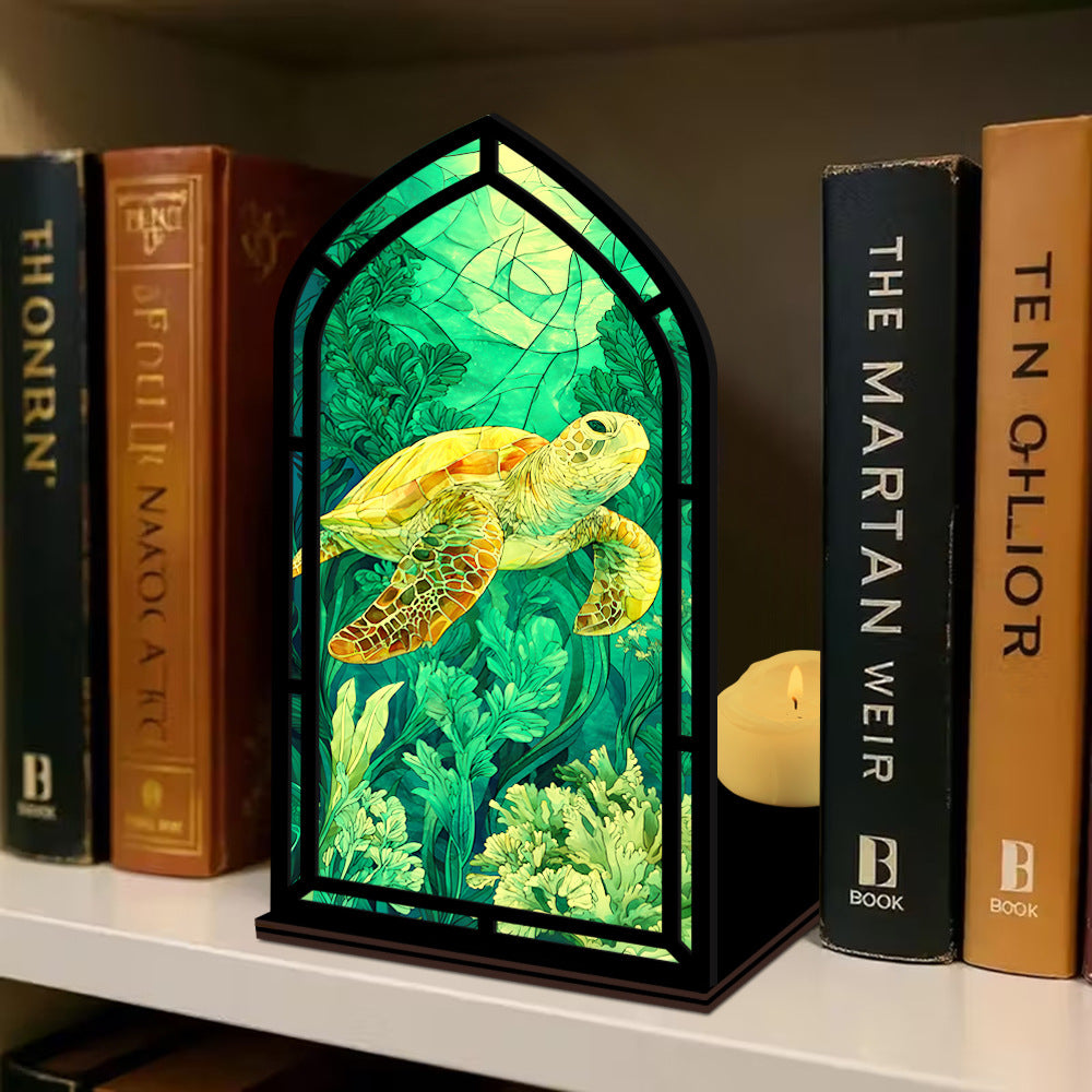 Book nook display with sea turtle panel in black arched frame, flanked by books