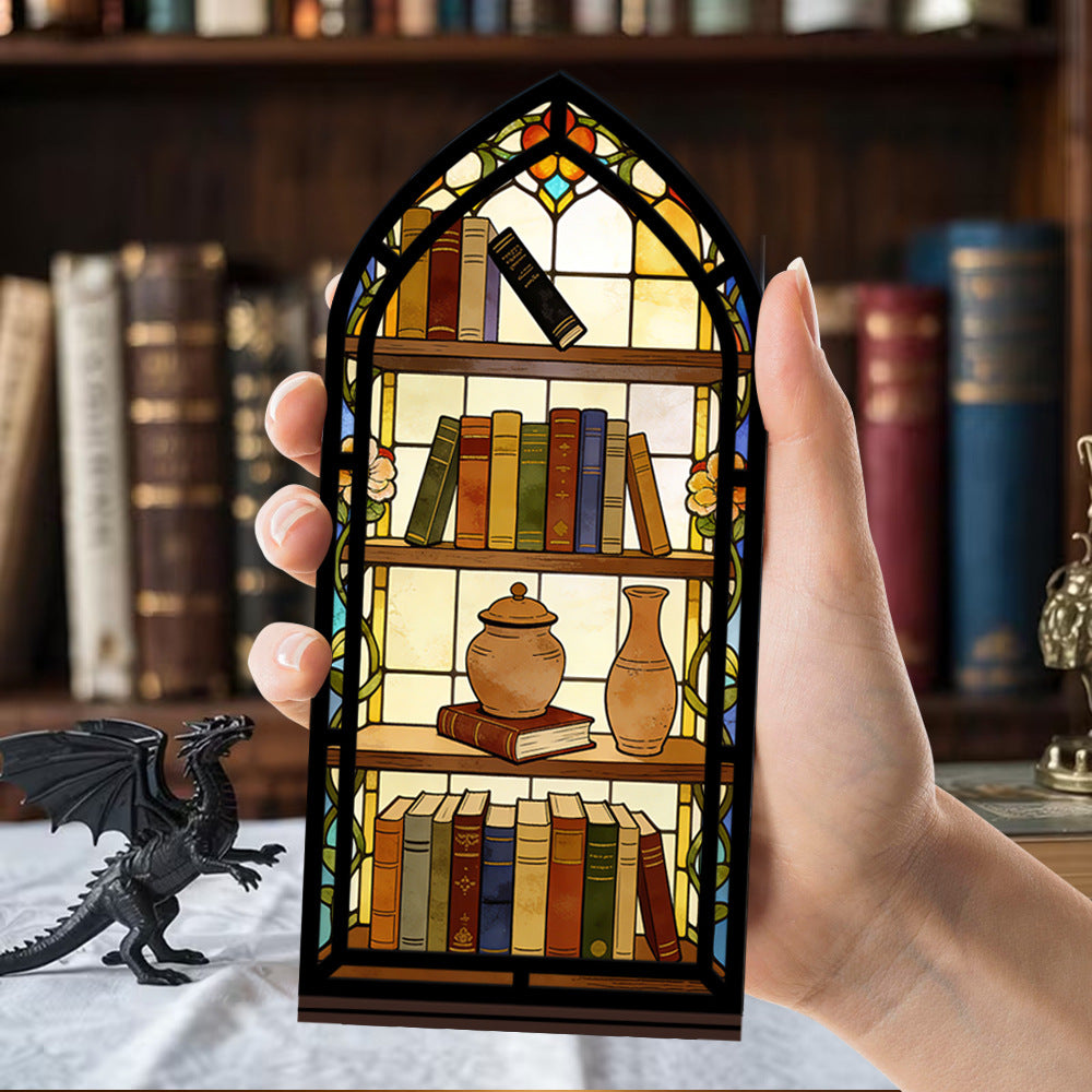 Arched illuminated book nook held by hands; faux books, teapot, and candle-glow panel.