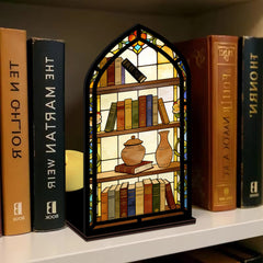 Arched illuminated book nook with faux books and apothecary jars on a black base.